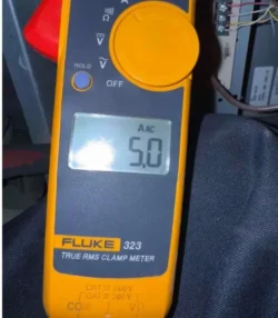 HVAC technician using Fluke clamp meter showing 5.0 amps during AC diagnostic in Riverside home