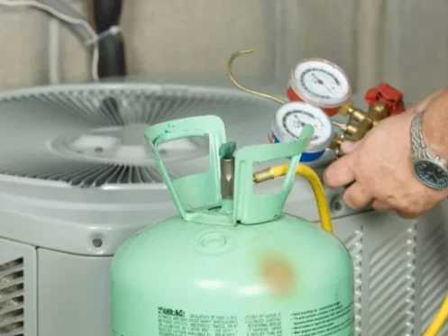 Closeup of refrigerant tank and gauges connected to AC unit
