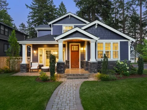 Modern home exterior with warm lights and green lawn