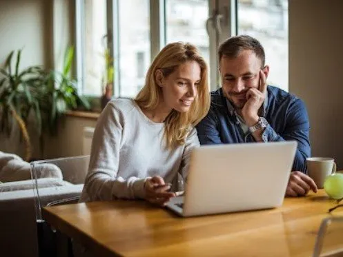 Happy couple using laptop to book HVAC service online