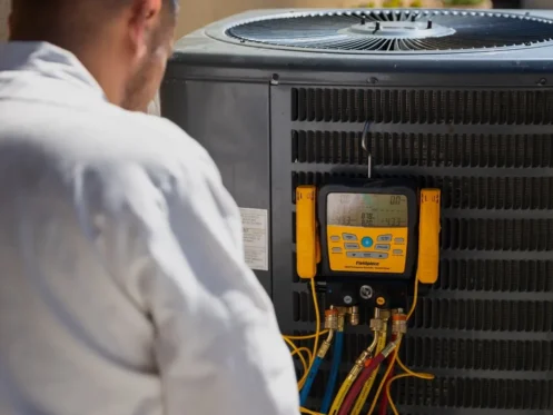 Technician checking outdoor AC unit pressure levels