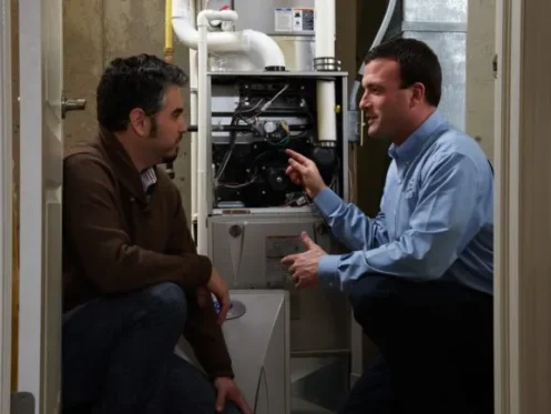Technician explaining furnace system components to homeowner