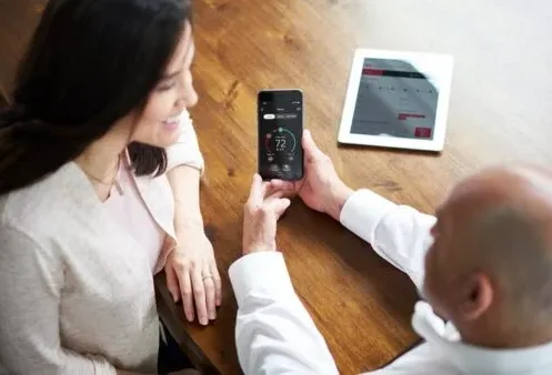Technician showing smart thermostat controls to customer