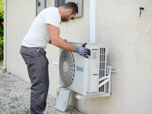 Technician installing wall-mounted AC condenser unit