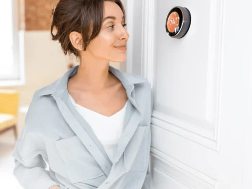 Woman checking a smart thermostat set at 74 degrees inside a modern home